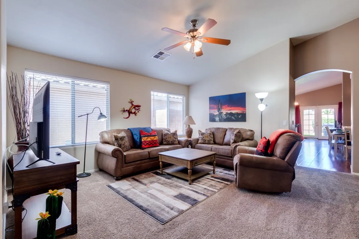 A comfortable and inviting living room scene, featuring a sofa set, coffee table, television, and artwork on the wall. The space is arranged for relaxation, movie nights, or entertaining guests, with soft lighting that adds to the cozy atmosphere.