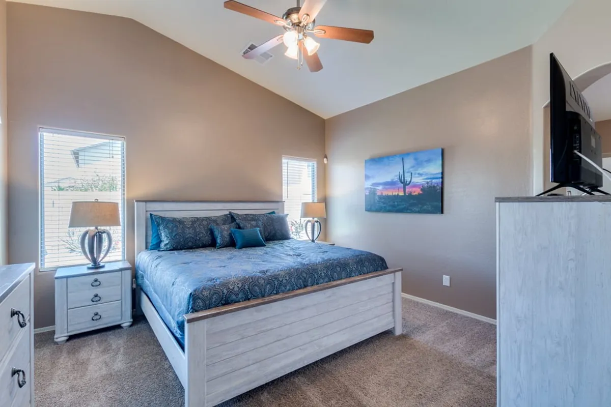 A serene bedroom featuring a plush bed with crisp linens, matching nightstands, soft lighting from a bedside lamp, and tasteful wall art, creating an inviting and restful ambiance.