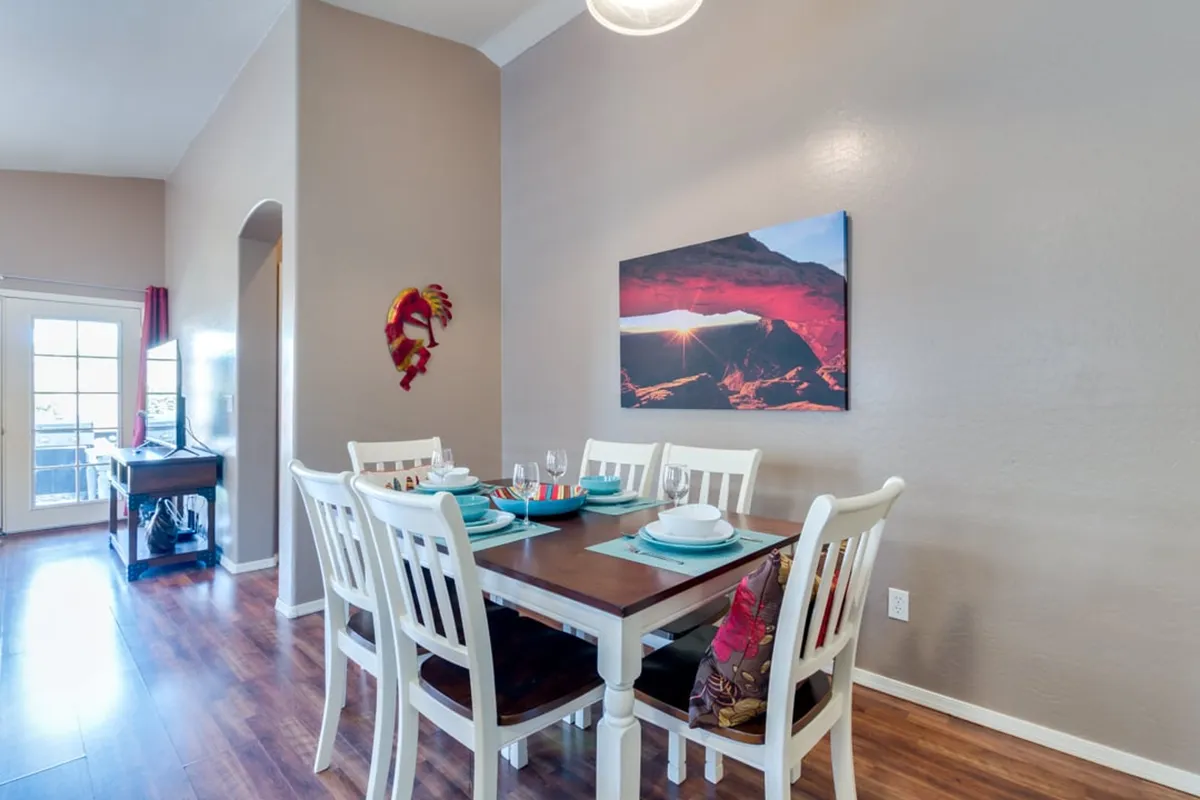 A bright, welcoming dining area with a well-appointed dining table, stylish wall art, and a colorful decorative pillow nearby. The setup suggests shared meals and easy conversation, making it feel ideal for family dinners or holiday celebrations.